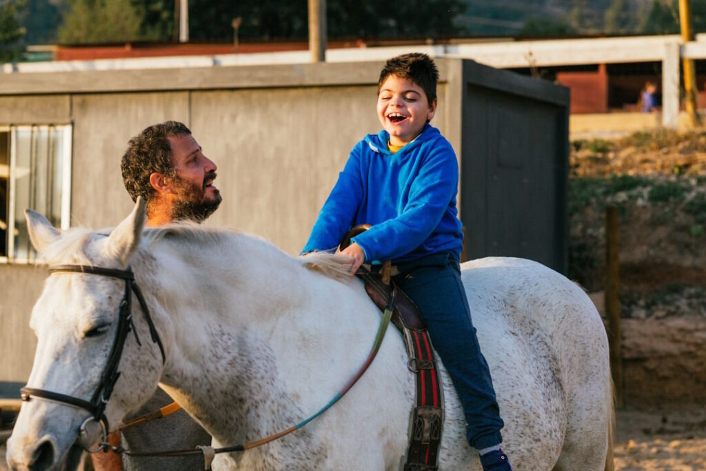 Happy handicapped boy riding a horse during equine therapy